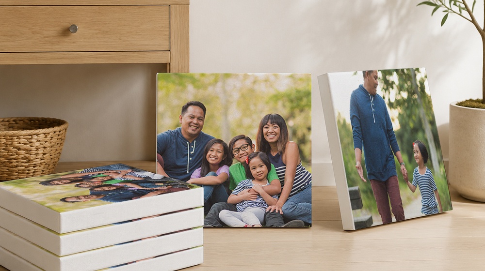 Family photo canvas prints displayed beside a stack of canvases.