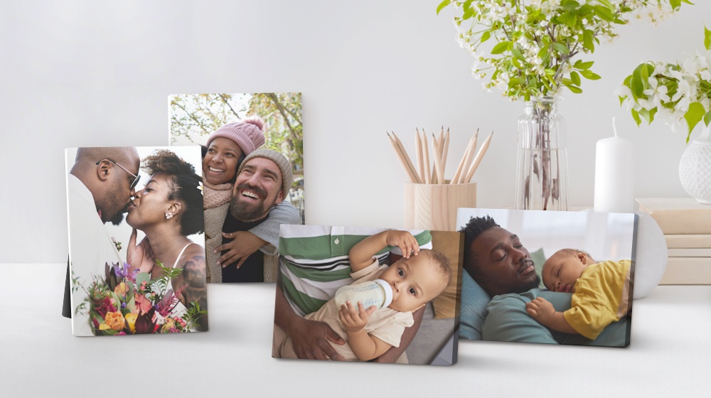 four desktop canvases sitting atop a desk depicting a collection of family photos