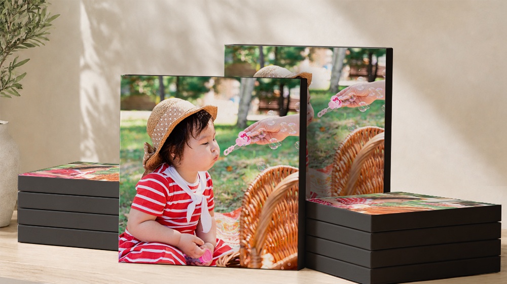 Canvas prints of a child blowing bubbles, displayed beside stacked canvases.