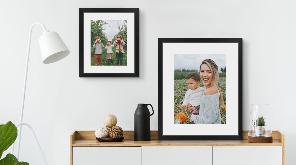 Two framed prints over a cabinet featuring a autumn family photos