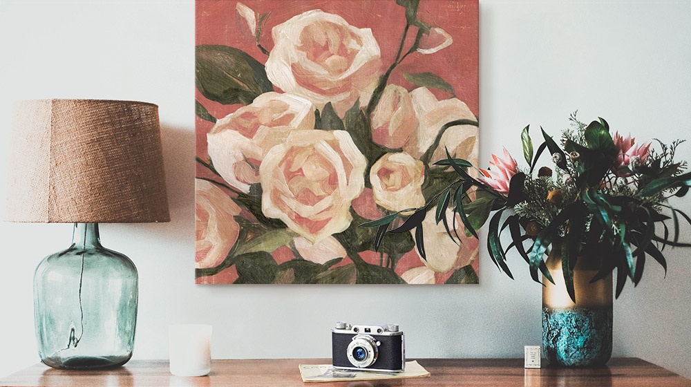 floral canvas hanging above table with lamp and camera and plant