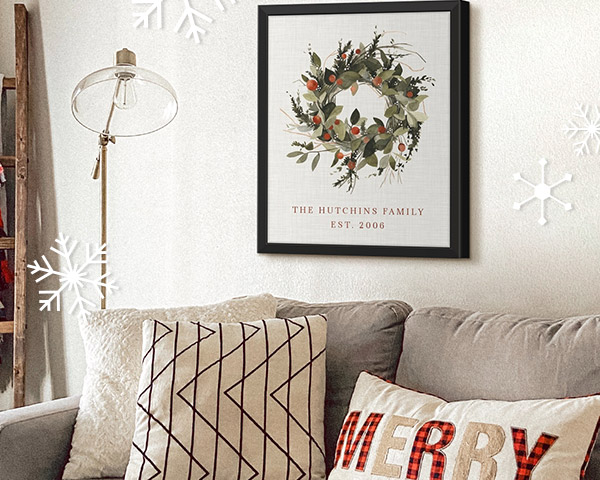 a holiday wreath design printed on canvas with a family name hung on a wall